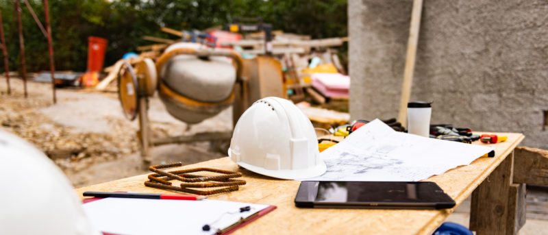 Construction blueprint, hardhat and tools on table